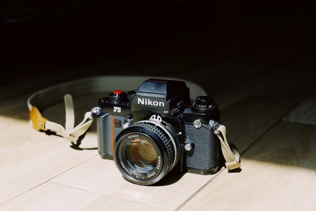 a camera sitting on a wooden floor with a strap around it (Photo: cling_yong / Unsplash)
